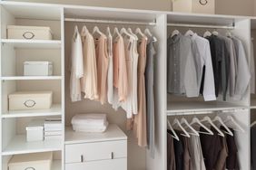 modern closet with clothes hanging on rail, white wooden wardrobe, interior design concept