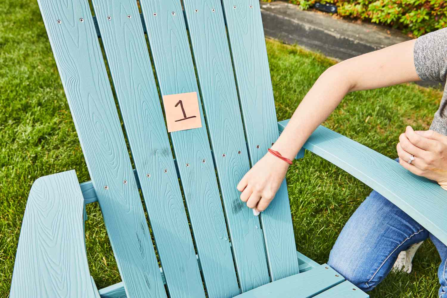 Woman cleaning dirty stains from Yefu Plastic Adirondack Chair outside 