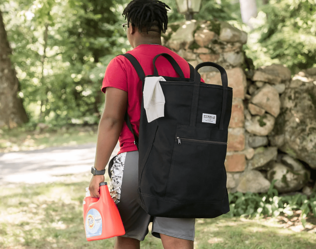 a man holding laundry detergent with a laundry backpack on