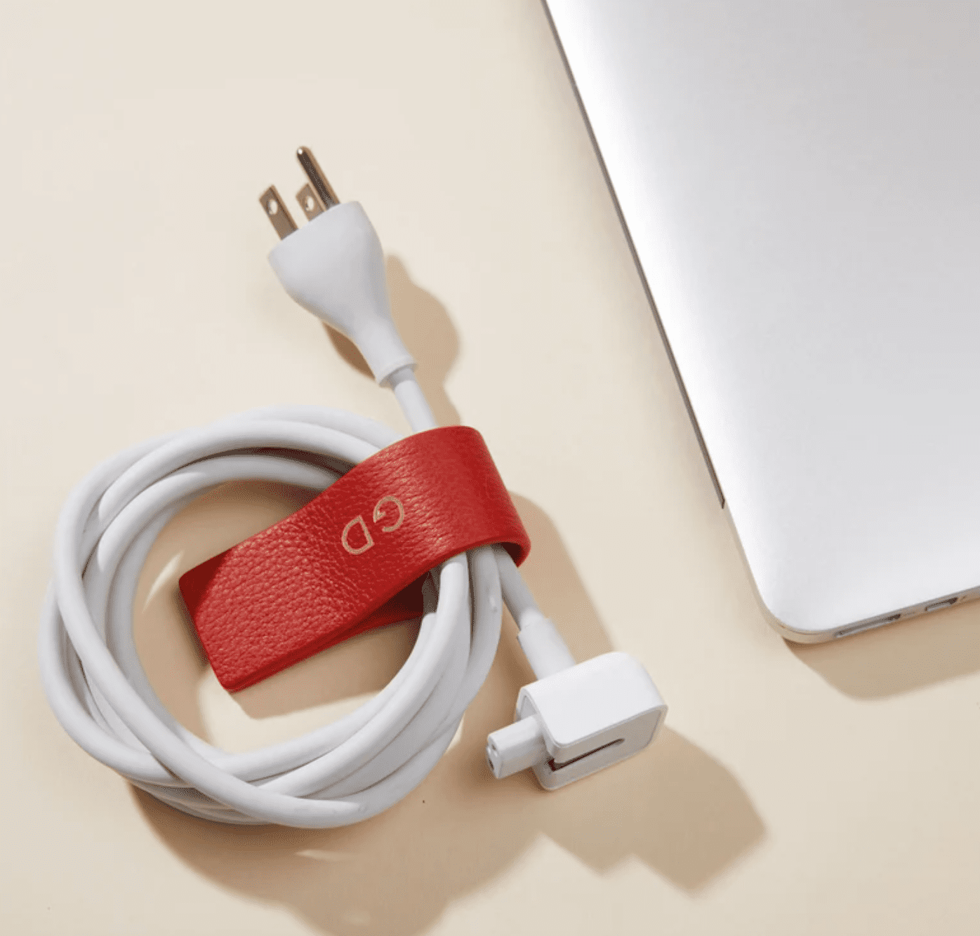 a red leather cord wrap with a cord next to a computer